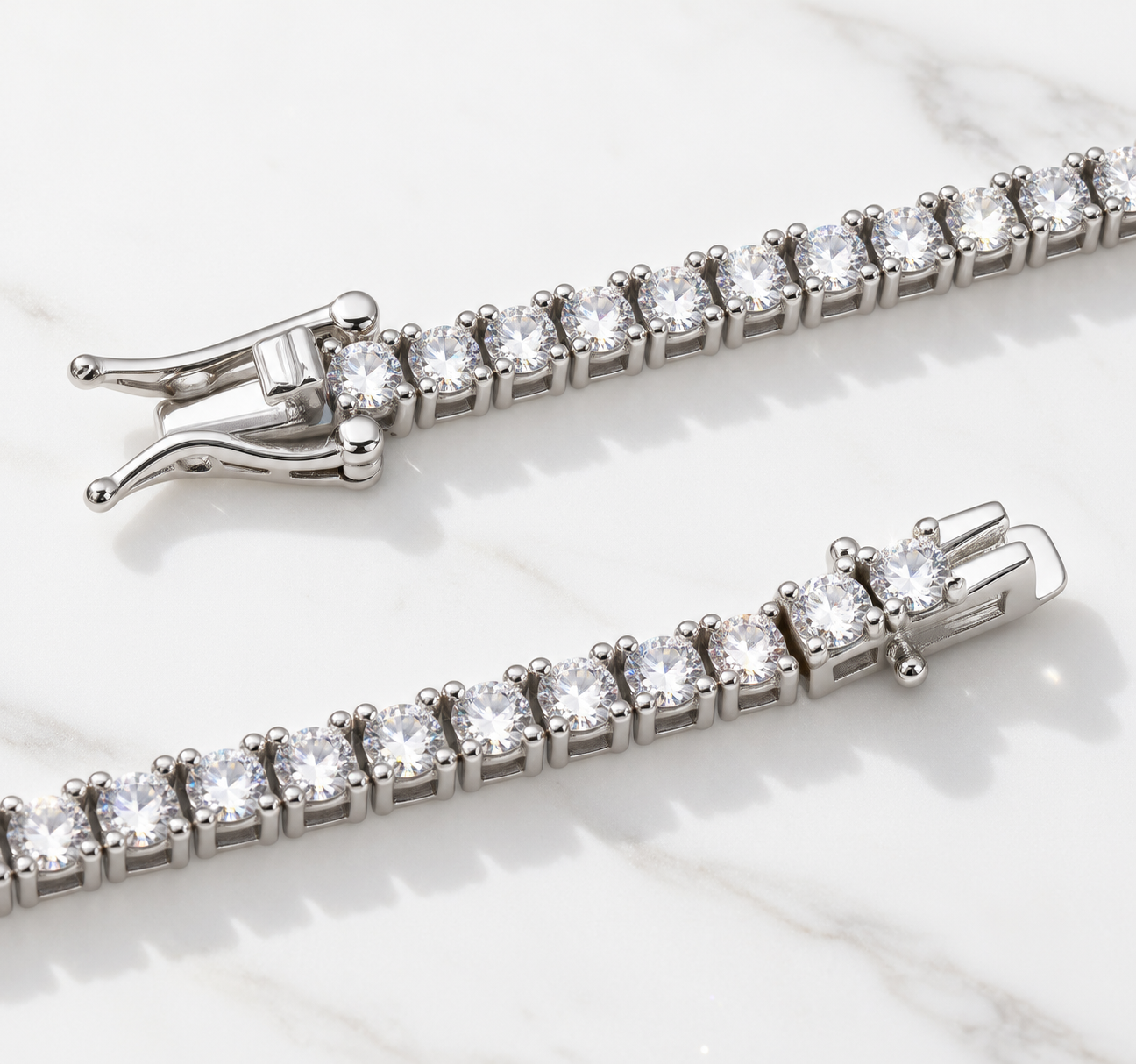 Two cubic zirconia tennis chains on marble, showing the four-prong settings and the box clasp